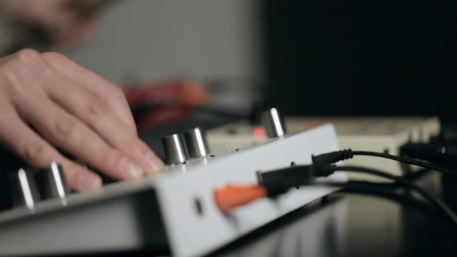 Close up shot of musician's hand tune synthesizer and plays electronic percussion