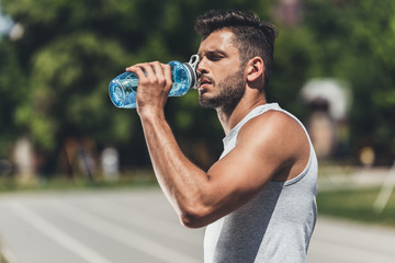 sporty young man drinking water after workout