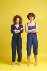 Relationship problems. Two young charming girls keeps hands crossed, offended at each other. A grim...