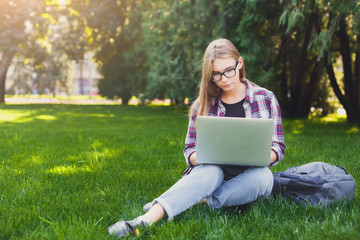 Serious young woman using laptop in park