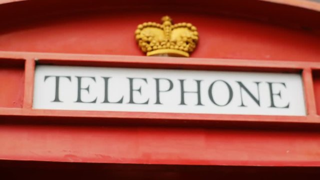 closeup view of the inscription TELEPHONE on red phone booth with crown decoration britain style call box worldwide communication concept connection development telecommunication british payphone