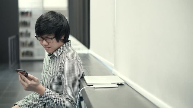 Young Asian business man using smartphone on social media application and playing game at break time in office. Urban lifestyle in working space concept. 4K video
