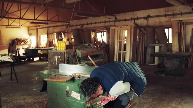 Man worker having an accident in the carpentry workshop.