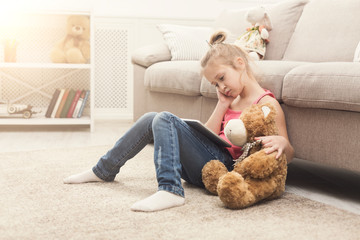 Little girl with tablet sitting on floor at home