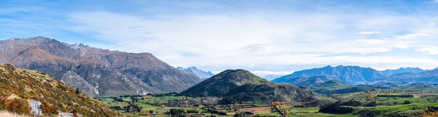 Panorama view of a beautiful road between Queenstown and Wanaka via Crown range. Grassland autumn trees with beautiful landscape of rocky mountains.