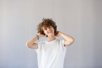 Сoncept dizzying success. Young wonderful girl keeps herself for curly head, rejoices in her...