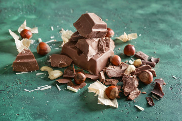 Tasty chocolate with hazelnuts on color background