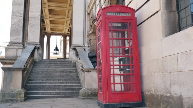 A Red telephone booth by an old building.
