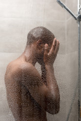 side view of young african american man washing body in shower