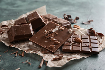 Pieces of chocolate with almonds on color background