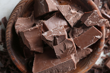 Bowl with pieces of chocolate on table, closeup
