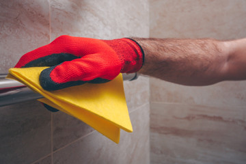 A man in gloves diligently to shine rub a new towel warmer, a thorough cleaning of the apartment