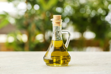Jug with olive oil on table against blurred background