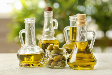 Jugs with olive oil on table against blurred background