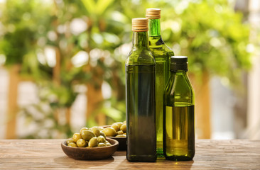 Bottles with olive oil on table against blurred background
