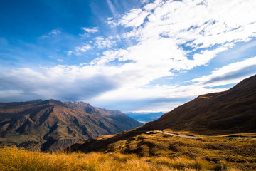 The beautiful road between Queenstown and Wanaka via Crown range. Grassland and beautiful landscape of rocky mountains.