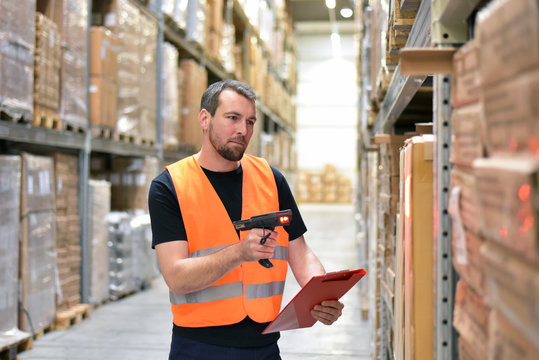 logistician in a warehouse of a forwarding agency scans packages for dispatch // Arbeiter in einer Spedition im Warenlager - Transport von Gütern im Onlinehandel 