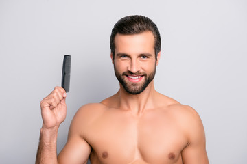 Fototapeta premium Close up portrait of satisfied glad excited cheerful virile masculine muscular bearded with toothy smile handsome guy demonstrating comb isolated on gray background