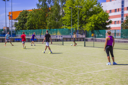 Teenagers play mini football on an artificial surface.