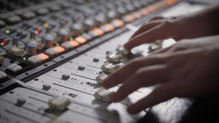 Close up shot of professional dj's hands working with a recording board in studio.