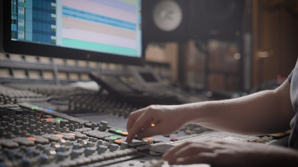 close up shot of the recording engineer, who mixes the tracks in his office, the man holds his...