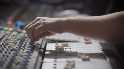 sound engineer is reducing signals from sources and applying effects on a recorded sound in a studio