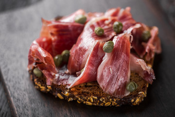 Traditional Spanish Jamon Serrano ham, Prosciutto Crudo, Parma ham, Italian antipasto, served on toasted bread.