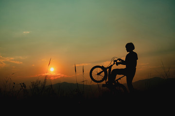 Fototapeta na wymiar silhouette of a girl riding on a trail with his bike.
