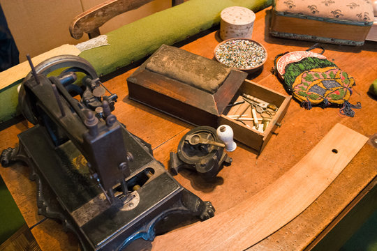 Antique sewing machine resting on a table and surrounded by other tailoring tools.