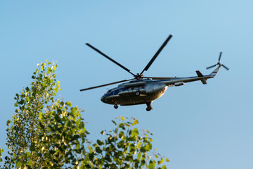 civil helicopter in the air against the sky and green tree