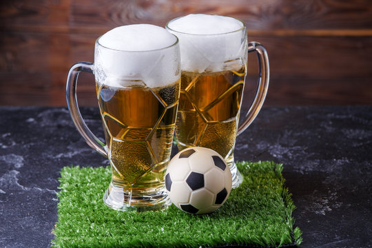 Image of two glasses of beer, soccer ball on green grass