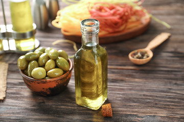 Bottle with oil and olives on wooden table