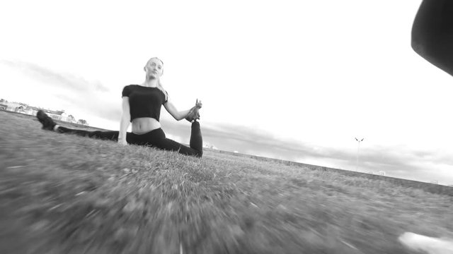 Gymnastic training outdoor - girl performs split on the grass