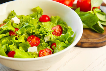 Bowl with fresh vegetable salad on table