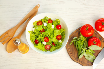Bottle with olive oil and fresh vegetable salad on table