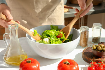 Obraz na płótnie Canvas Woman preparing tasty vegetable salad on table
