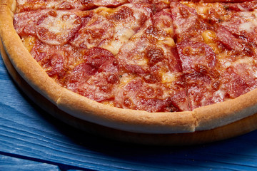 Salami pizza./sliced whole salami pizza on a wooden table