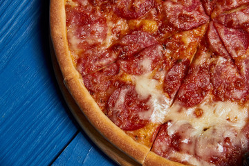 Salami pizza./sliced whole salami pizza on a wooden table