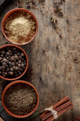 Spices in three ceramic bowls on the wooden background, close-up, selective focus, vertical