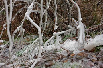 View of rocks and branches covered with ice on a cold winter day.