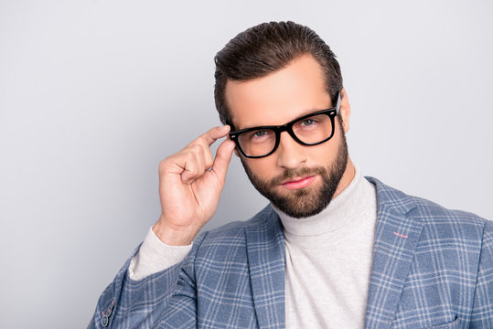 Portrait of gentlemen, manly, stunning, dreamy, inteligent man holding eyelet of glasses on his face with fingers, looking at camera over gray background
