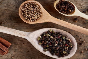 Aromatic various spices for cooking in wooden scoops on old wooden board, close-up, flat lay, shallow depth of field.