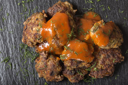 Romanian traditional food "chiftele" or "parjoale" with tomato sauce