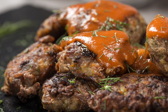 Romanian traditional food "chiftele" or "parjoale" with tomato sauce