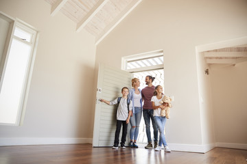 Family Opening Door And Walking In Empty Lounge Of New Home