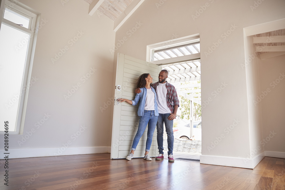 Wall mural Couple Opening Door And Walking In Empty Lounge Of New Home