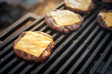 Preparing beef cutlet with cheese for burgers on the grill. Street food. Picnic on the street.