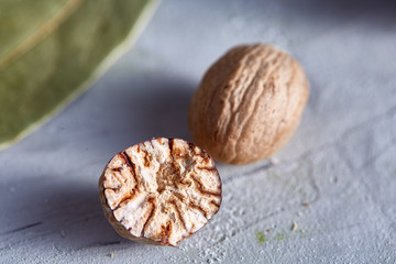 Bay leaf and nutmeg on white textured background, top view, close-up, selective focus.