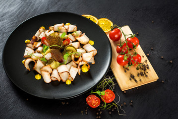 dish of many pieces of lard with vegetables on black background