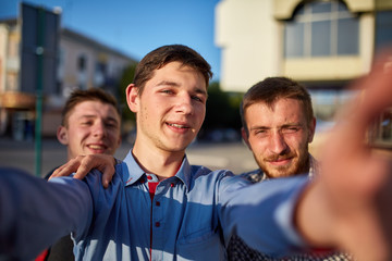 Portrait of a group of smiling and grin friends on summer holiday, making selfie on camera on urban background.